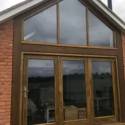 Triple bifolding door and feature apex window complete with a stained finish