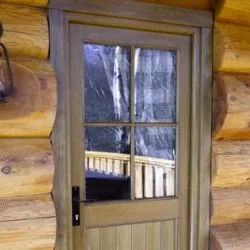 Back door of log cabin with boarded base and glazed top with Georgian bar